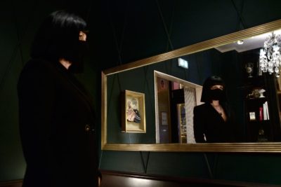 Claire D. en veste longue, masque et perruque noires photographiée à l'Hôtel la Mondaine par le photographe de boudoir - Paris
