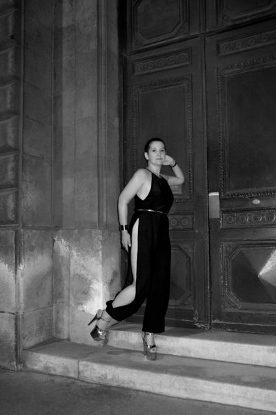 Claire D. en combinaison noire fendue photographiée en noir et blanc dans la rue Guénégaud à Paris par le photographe de boudoir