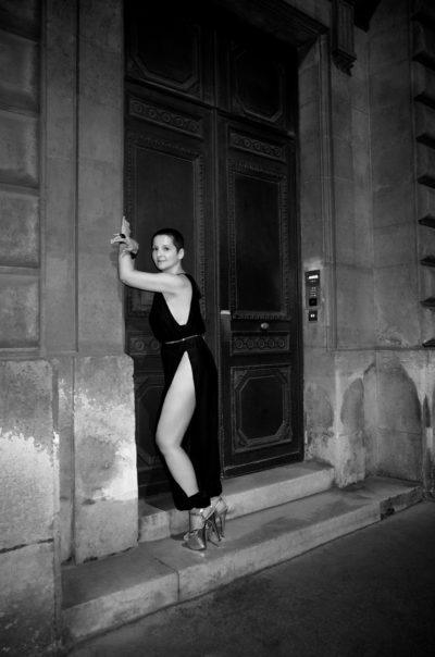 Claire D. en combinaison noire fendue photographiée en noir et blanc dans la rue Guénégaud à Paris par le photographe de boudoir